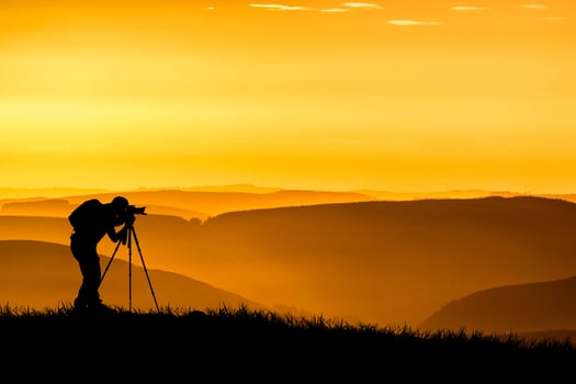 A professional photographer's silhouette is focused on shooting in a beautiful meadow. photo