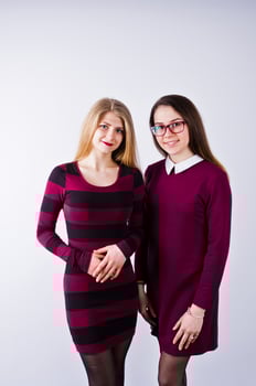 Portrait of two female friends in cherry dresses posing in the studio. photo
