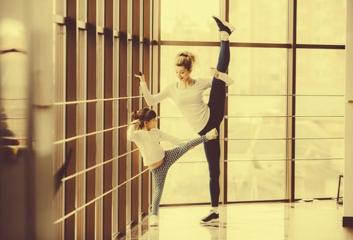 Mother learning daughter to make a high leg strech photo