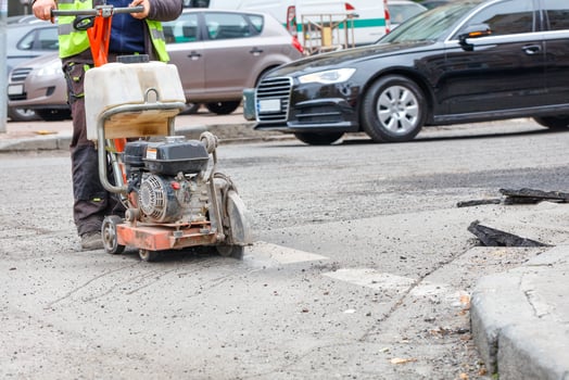 A road worker cuts with a gasoline cutter the destroyed old asphalt on the roadway for the subsequent repair of the road surface. photo