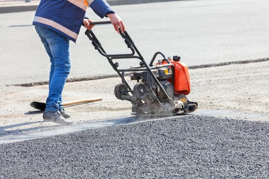 A road maintenance worker compacts asphalt with a petrol vibrating compactor. photo