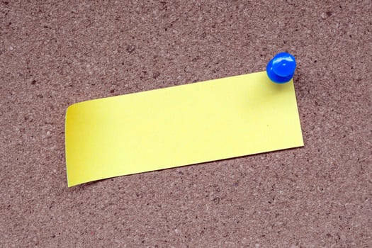 Yellow stick note and pinned to a cork notice board. Copy space. photo