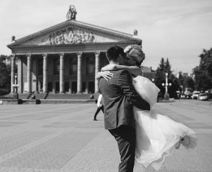 groom holds bride in his arms and twisted photo