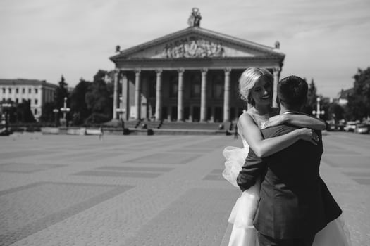 groom holds bride in his arms and twisted photo