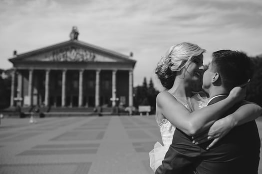 groom holds bride in his arms and twisted photo