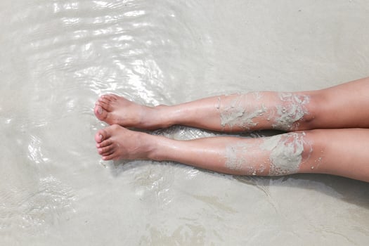 leg or bare woman feet in the ocean on sand beach photo