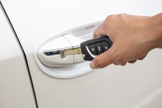 Closeup of a woman's hand inserting a key into the door lock of a white car. photo