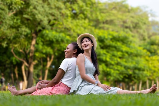 Diversity of LGBTQ lesbian couple is relaxingly sitting together on the grass lawn in public park during summer season to enjoy the leisure time concept photo