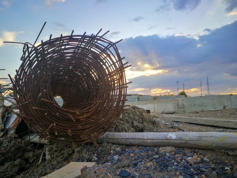 Rusted steel rolls in construction projects. Steel and bamboo on clay and stone piles photo