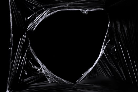 a black transparent plastic texture with hole for poster and cover art. realistic plastic wrap for overlay, copy space and photo effect. wrinkled plastic surface on black background