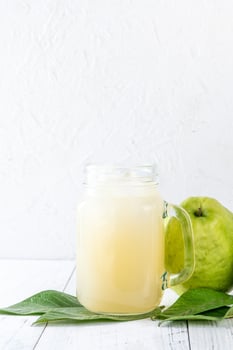 Delicious guava fruit with fresh juice set on white wooden table background. photo
