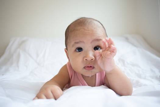 Asian cute baby in white sunny bedroom. Newborn child relaxing on bed photo