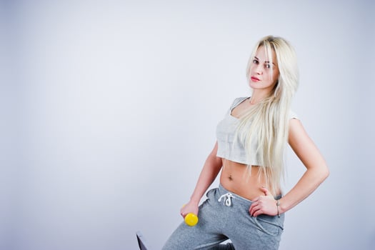 Blonde sporty girl with yellow dumbbell posed at studio against white background. photo