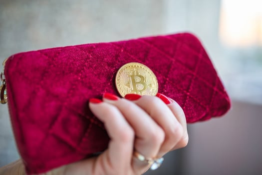 virtual money golden bitcoin on pink women fabric purse. fingers with red nails on a coin photo