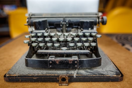 old vintage dust-covered typewriter with sheet of white paper photo