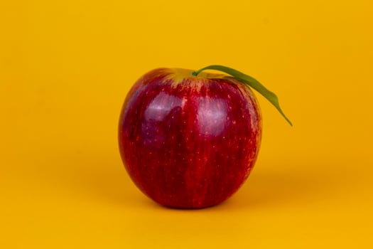 A red apples isolated on yellow background. Organic red apple fruit used for healthy fruit concept  with clipping path and full depth of field photo