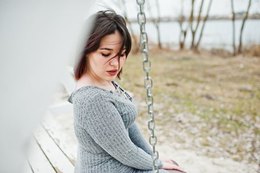 Portrait of brunette girl in gray dress sitting at white wooden construction. photo