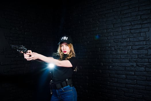 FBI female agent in cap and with gun at studio against dark brick wall. photo