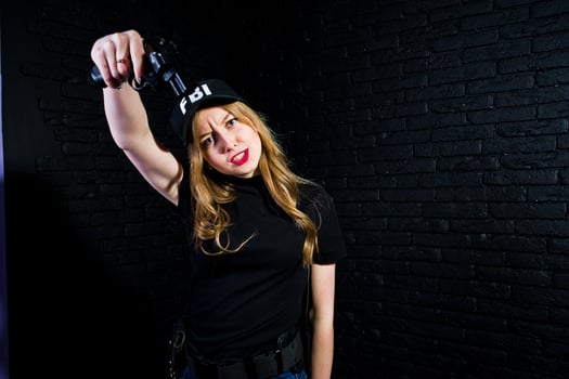 FBI female agent in cap and with gun at studio against dark brick wall. photo