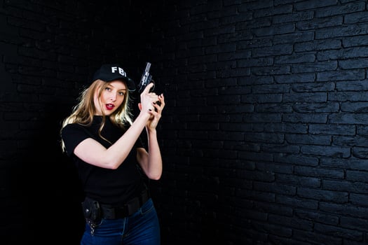 FBI female agent in cap and with gun at studio against dark brick wall. photo