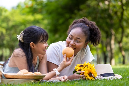 Couple of lesbian people having picnic in the park during summer while having snack and lying down on the lawn to celebrate pride month and marriage equality photo