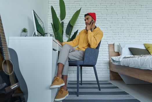 Young African man using computer while sitting at his working place at home photo