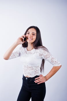 Portrait of a young beautiful woman in white top and black pants using her phone. photo