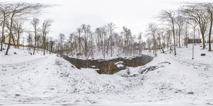 Winter full spherical seamless panorama 360 degrees angle view on road in a snowy park with gray pale sky near small river in equirectangular projection. VR AR content photo