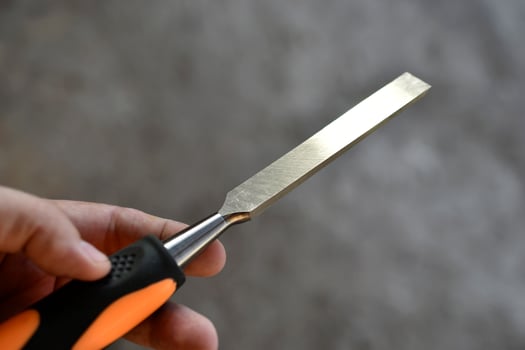 Steel chisel on wood in the hands. Carpentry iron hand tools. photo