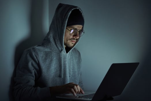 Confident young man in hooded shirt using computer while working late photo