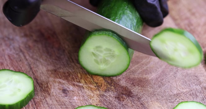 cut a ripe long green cucumber on a board photo