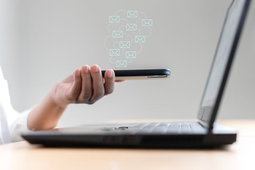 Woman hand holding mobile phone receive or send email icon on working desk with laptop photo