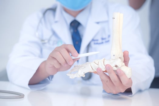 orthopedic doctor in his office with a patient and a model of the foot photo