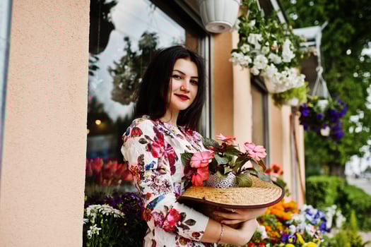 Summer portrait of brunette girl in pink glasses and hat against flowers shop. photo