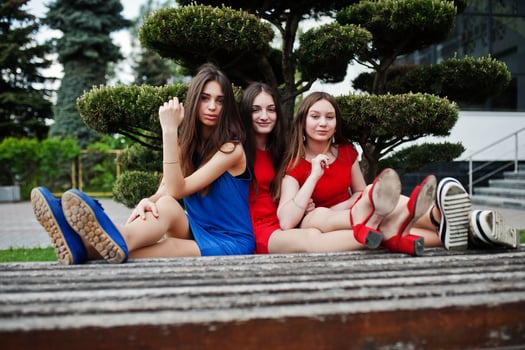 Three teenagers girl in blue and red dresses posed outdoor. photo