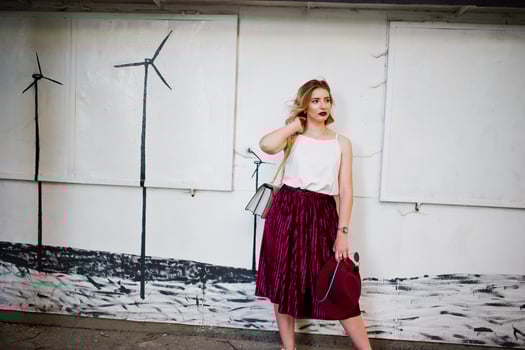 Fashionable and beautiful blonde model girl in stylish red velvet velour skirt, white blouse, hat and sunglasses, posed with phone and earphones. photo