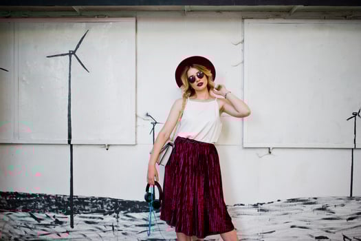 Fashionable and beautiful blonde model girl in stylish red velvet velour skirt, white blouse, hat and sunglasses, posed with phone and earphones. photo