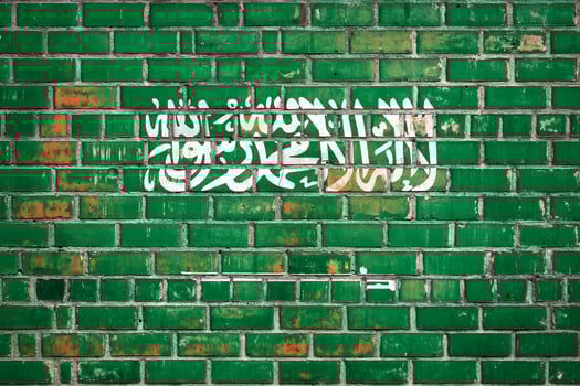 National  flag of the Saudi Arabia on a grunge brick background. photo