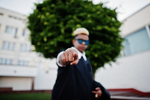 Stylish arabian muslim boy with originally hair and sunglasses posed on streets and show finger at camera. photo