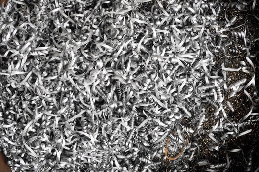 steel scrap materials recycling. aluminum chip waste after machining metal parts on a cnc lathe. closeup twisted spiral steel shavings. small roughness sharpness. photo