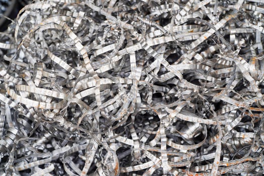 Steel scrap materials recycling. Aluminum chip waste after machining metal parts on a cnc lathe. Closeup twisted spiral steel shavings. Small roughness sharpness, photo