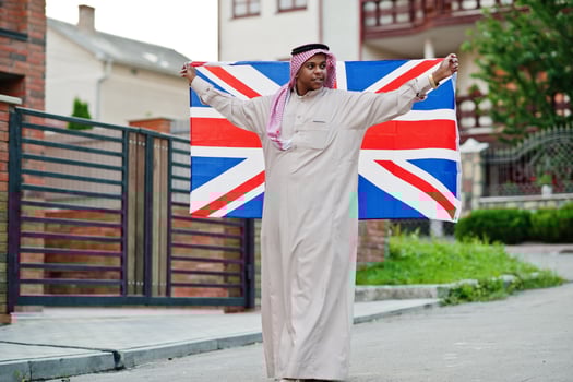 Middle Eastern arab man posed on street with Great Britain flag. England and Arabian countries concept. photo