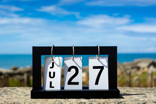 Jul 27 calendar date text on wooden frame with blurred background of ocean. photo