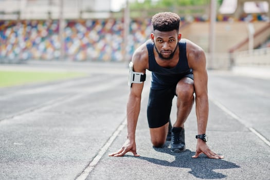 African american male athlete in sportswear racing alone down a running track at stadium. photo