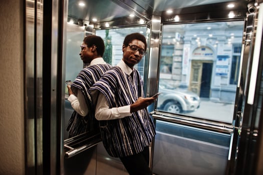 African man in traditional clothes and glasses with mobile phone at elavator or modern lift. photo