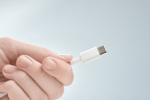 Fingers holding white type-c cable connector on a gray background. photo