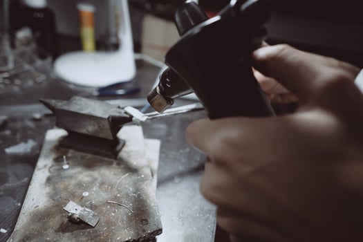 In the workshop, a woman jeweler is busy soldering jewelry photo