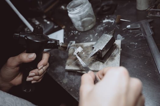 In the workshop, a woman jeweler is busy soldering jewelry photo