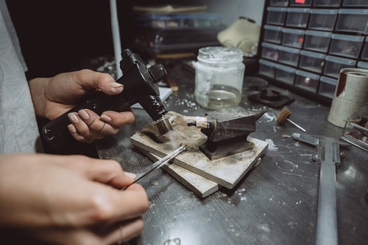 In the workshop, a woman jeweler is busy soldering jewelry photo