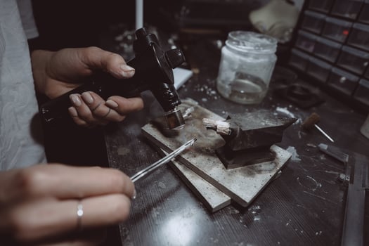 In the workshop, a woman jeweler is busy soldering jewelry photo